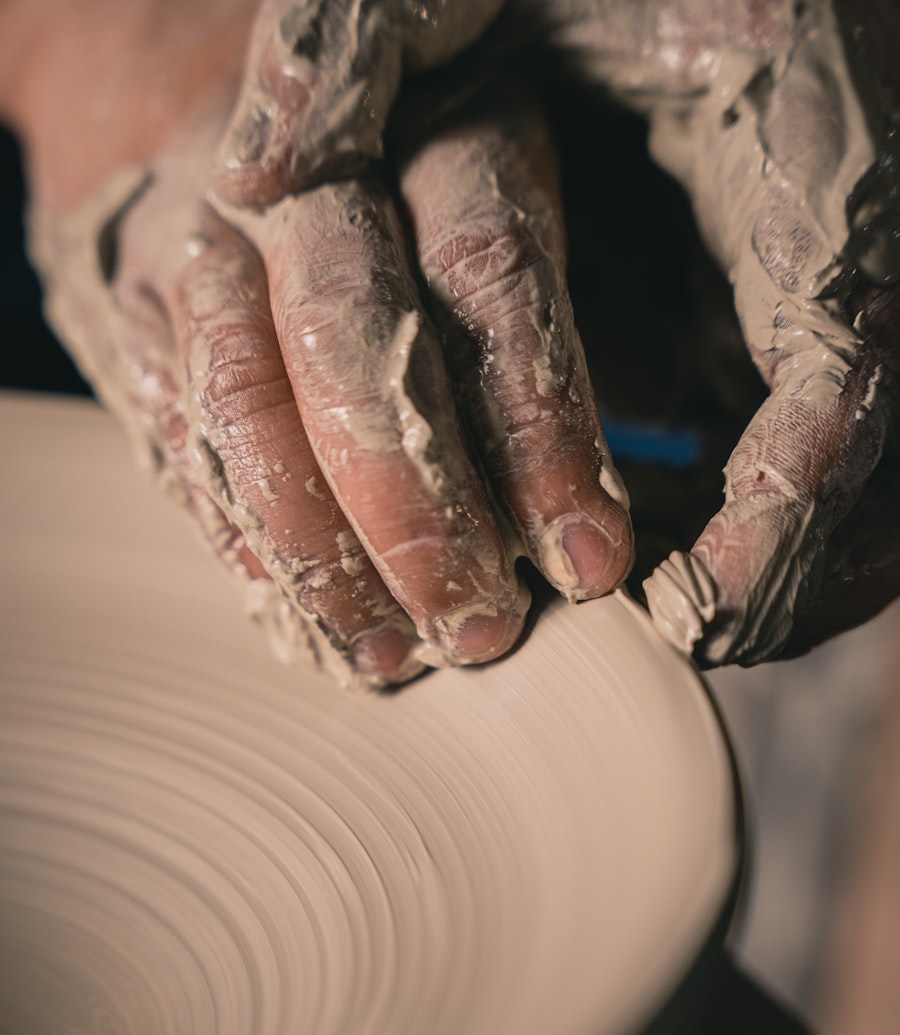 Clay-covered hands shaping a coil pot