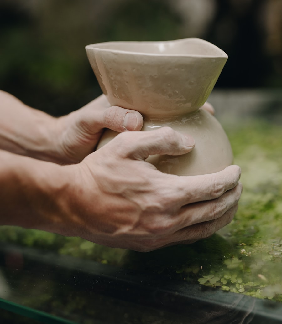 A student holding up the first vase they threw on the wheel