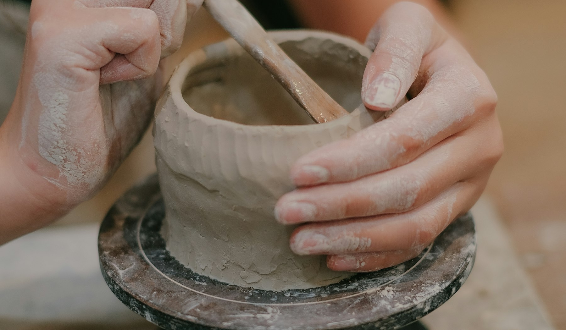 Hands shaping a pot on the wheel in the studio